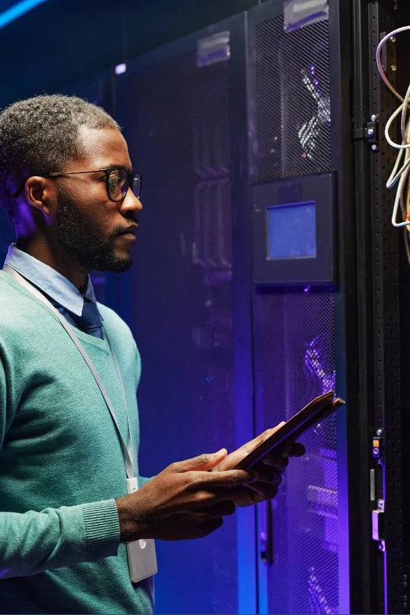 Technicien avec tablette devant une baie de serveurs